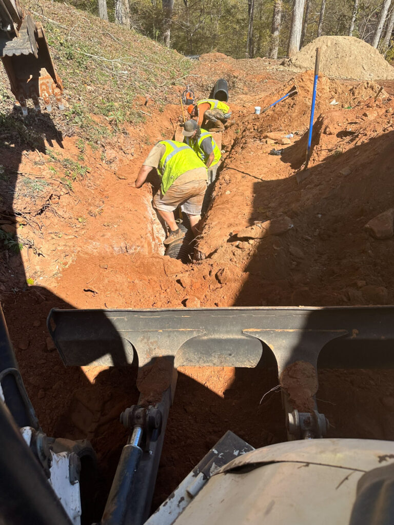utility contractor crew working in ditch installing new pipe