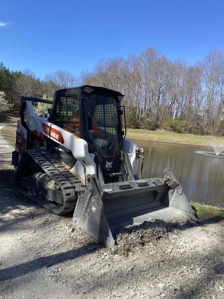 Francis Brothers crew member on a Bobcat grading a gravel driveway